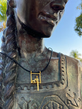Load image into Gallery viewer, Bronze statue with a gold necklace and black cord attached, outdoors.