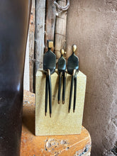 Load image into Gallery viewer, Three small black metal figurines shaped like seated human figures with gold-colored heads and hands
