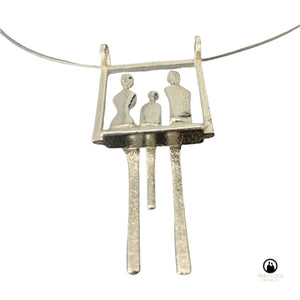 A mother and father with child in a swing in silver. Pendant shown from below
